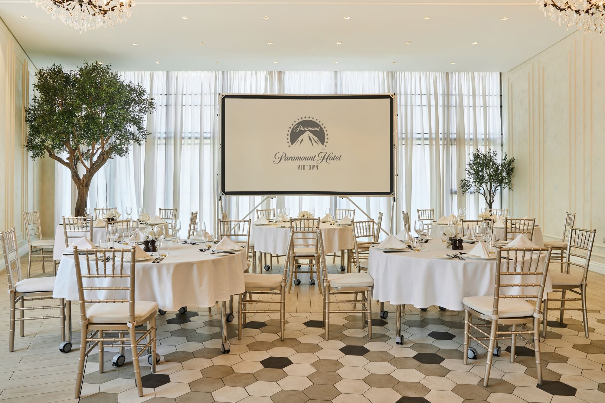 Dining table arrangements and plush carpeted floors in the Paparazzi restaurant event room at Paramount Hotel Midtown