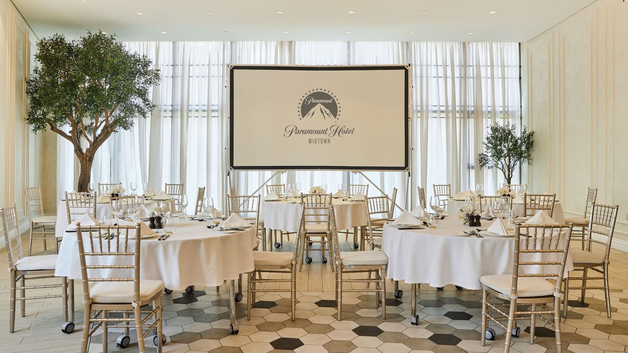 Spacious event venue at Paparazzi restaurant, Paramount Hotel Midtown, with set round tables and a projector screen