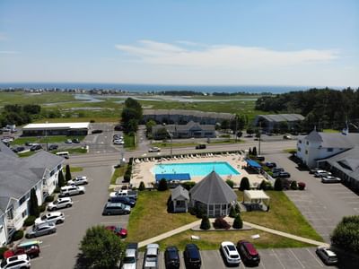 Aerial view of Ogunquit Hotel and Suites with large pool, parking lot, and coastal landscape under a clear blue sky