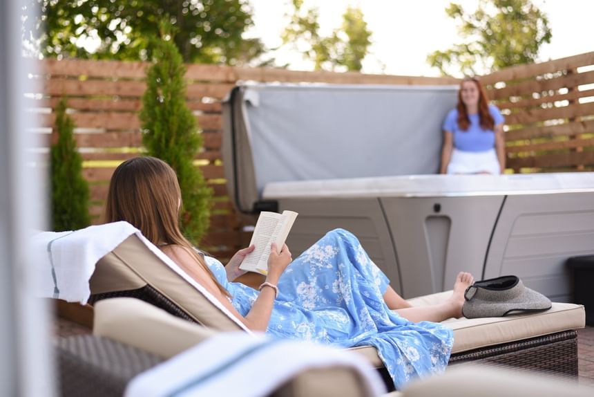 Woman reading on a lounge chair next to a woman in hot tub at one of the top PEI resorts, Rodd Crowbush Golf & Beach Resort