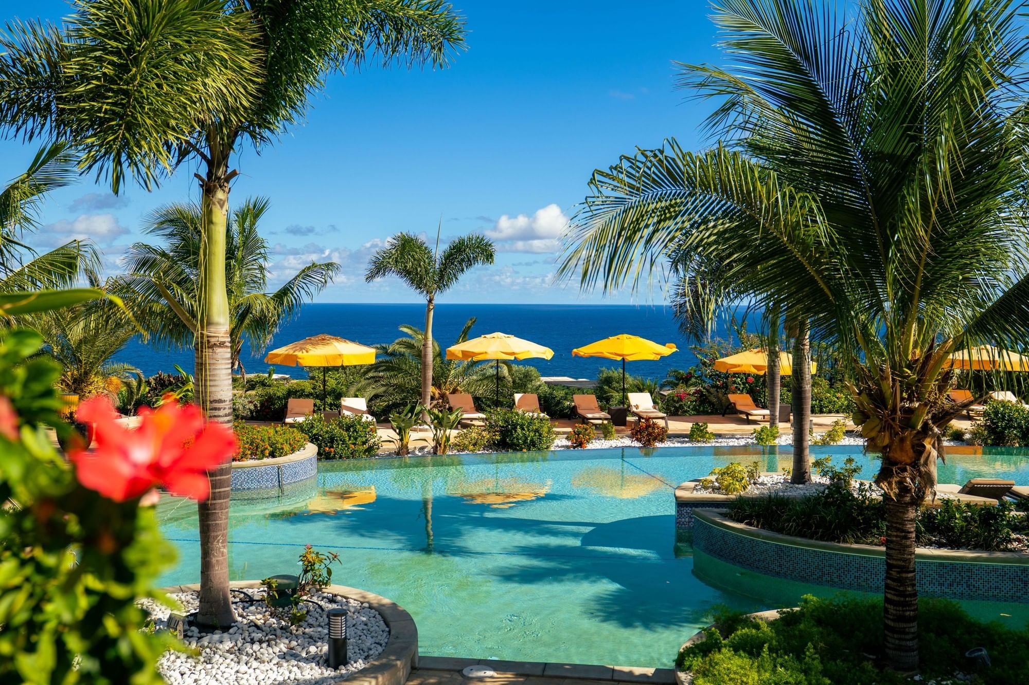Sunkissed swimming pool surrounded by tropical palm trees and yellow sun umbrellas at Golden Rock Resort