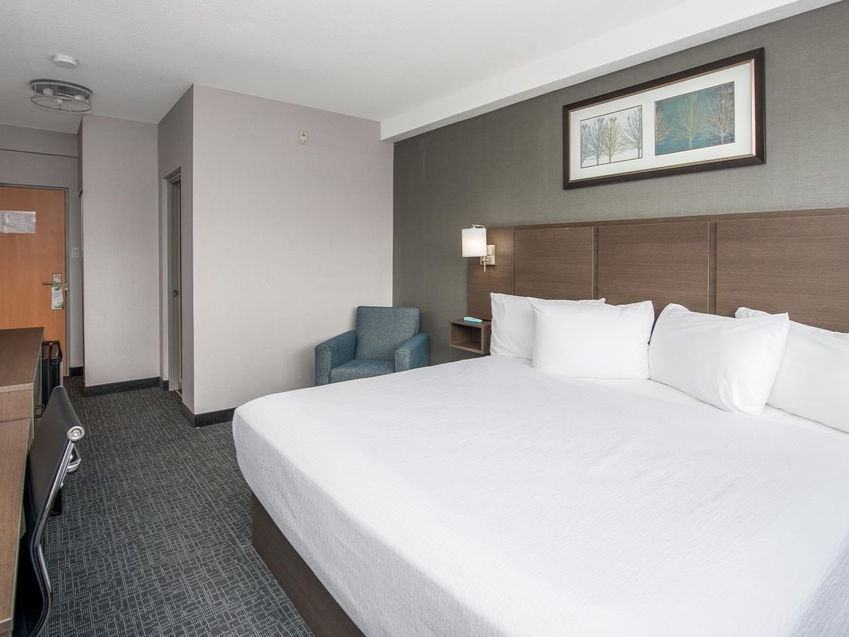 Room with a large bed, chair, and modern decor.