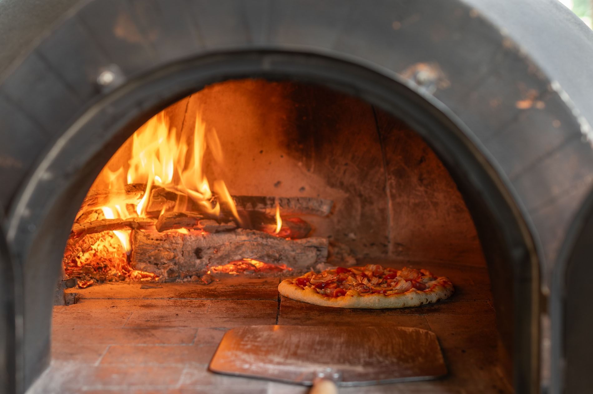 Deliciosa pizza horneándose junto a un fuego de leña ardiente dentro de un horno de piedra en Casa Santo Domingo
