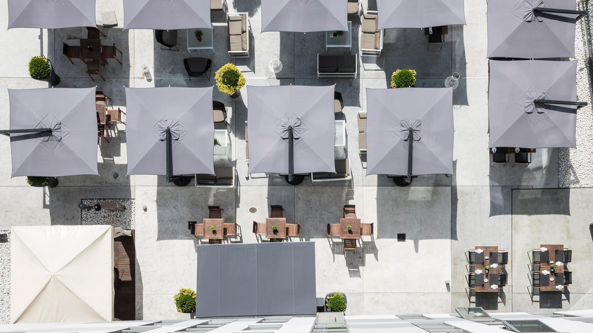 Aerial view of an outdoor patio with tables, chairs and grey umbrellas at Falkensteiner Hotel Belgrade