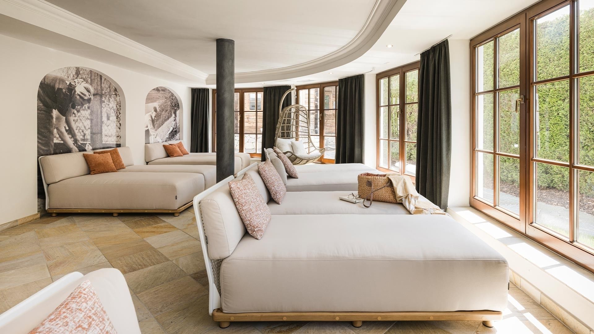 Geräumige Lounge mit hellen Sofas, großen Fenstern und Wanddekorationen in Schwarzweiß.