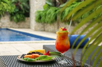 side table near pool with fruit plate and cocktail