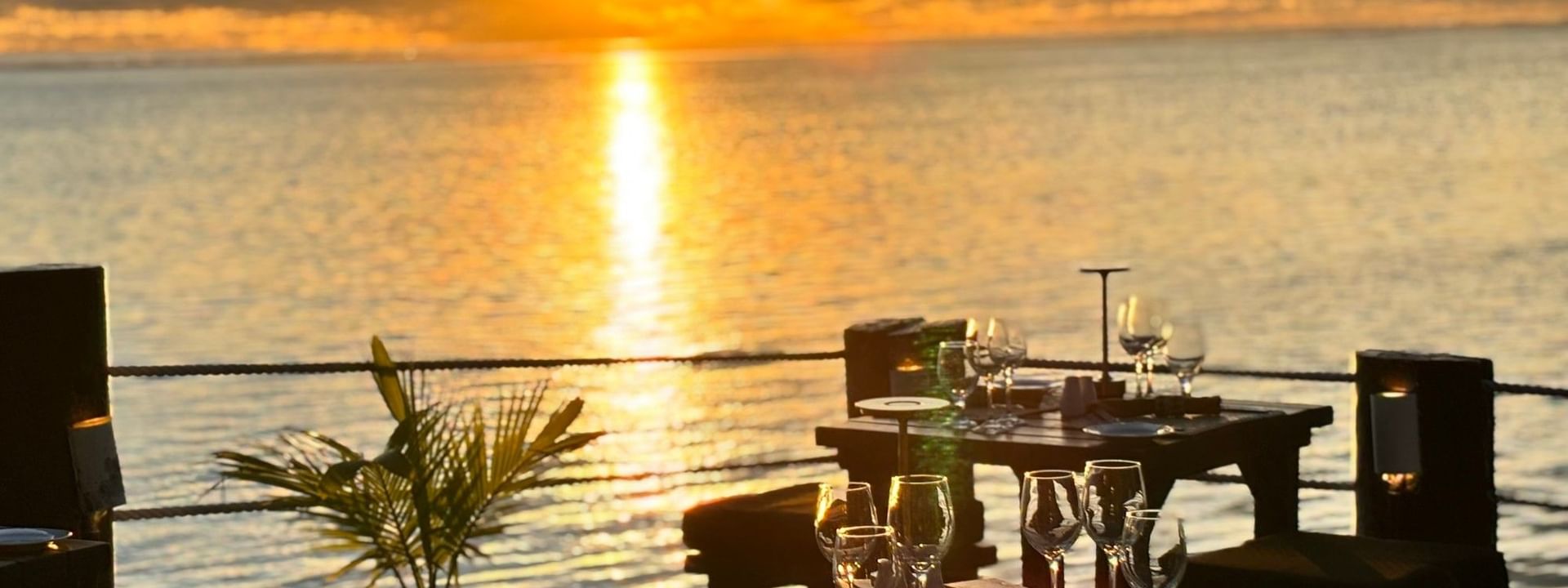 Sunset over ocean with Wicked Walu restaurant tables set for dinner at Warwick Fiji Resort and Spa, Korolevu
