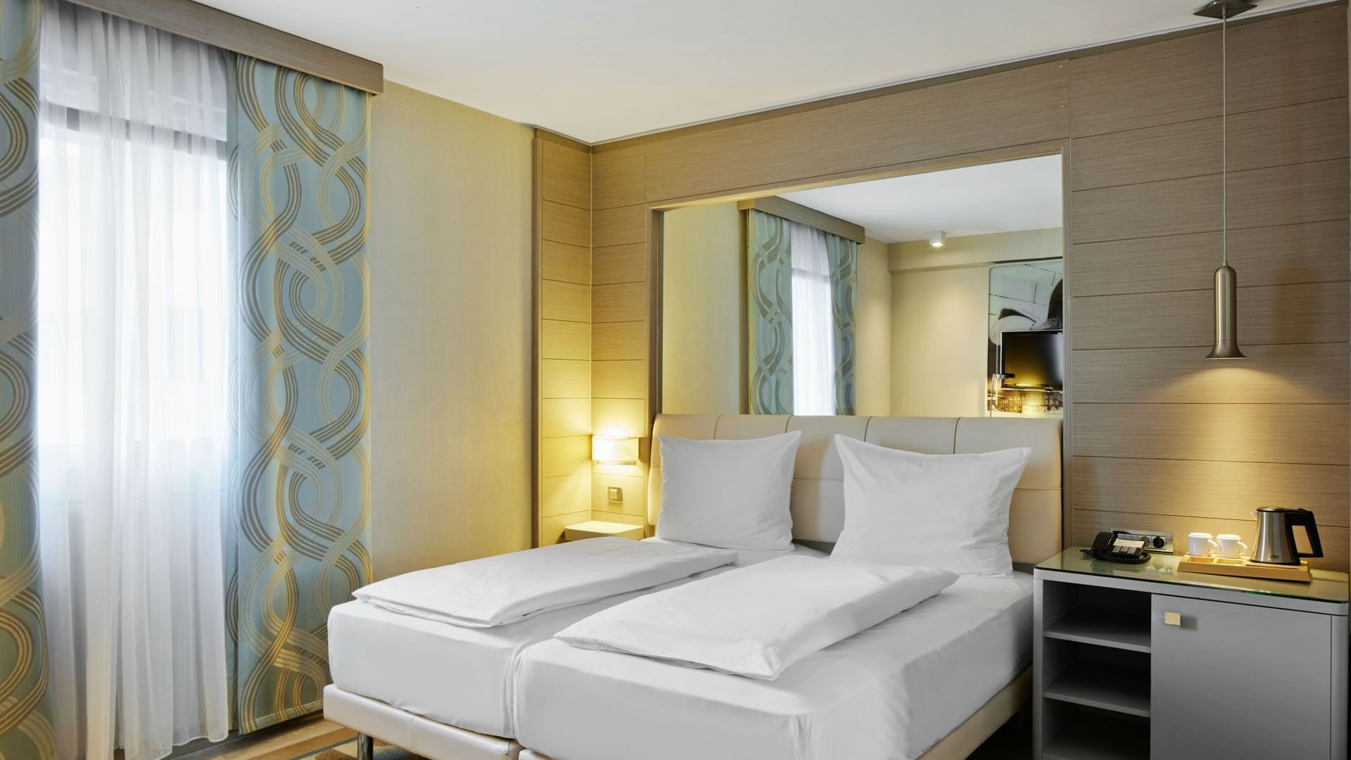 Superior Room with twin beds, a large mirror and a window at Titanic Comfort Mitte