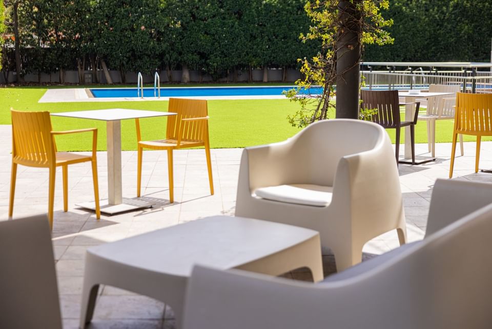 Lounge area by the pool with outdoor chairs & coffee tables at Hotel Vila Centric