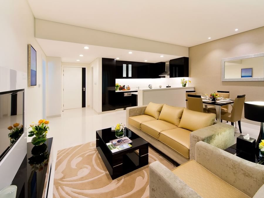 Modern living room with beige sofa, chairs, and adjacent open kitchen in One Bedroom at DAMAC Maison Aykon City