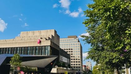 Crowd walking on a plaza by Place Des Arts under trees near Warwick Le Crystal Montreal