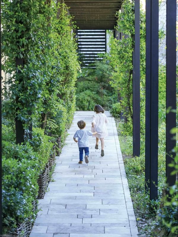Two toddlers running along a pathway at Domaine de Manville