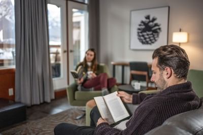 Couple reading books in the living room of Penthouse Suite at Blackstone Mountain Lodge