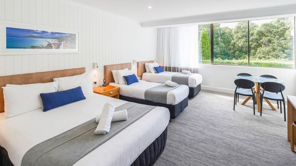 Double bed and twin single beds arranged by a dining table in Family Room with carpeted floors at Mercure Charlestown