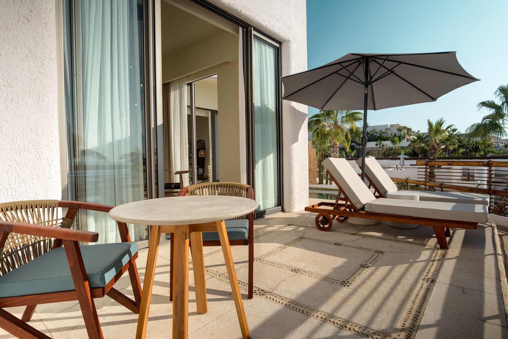 Spacious private balcony with lounge chairs and a dining table at Marquis Los Cabos Resort