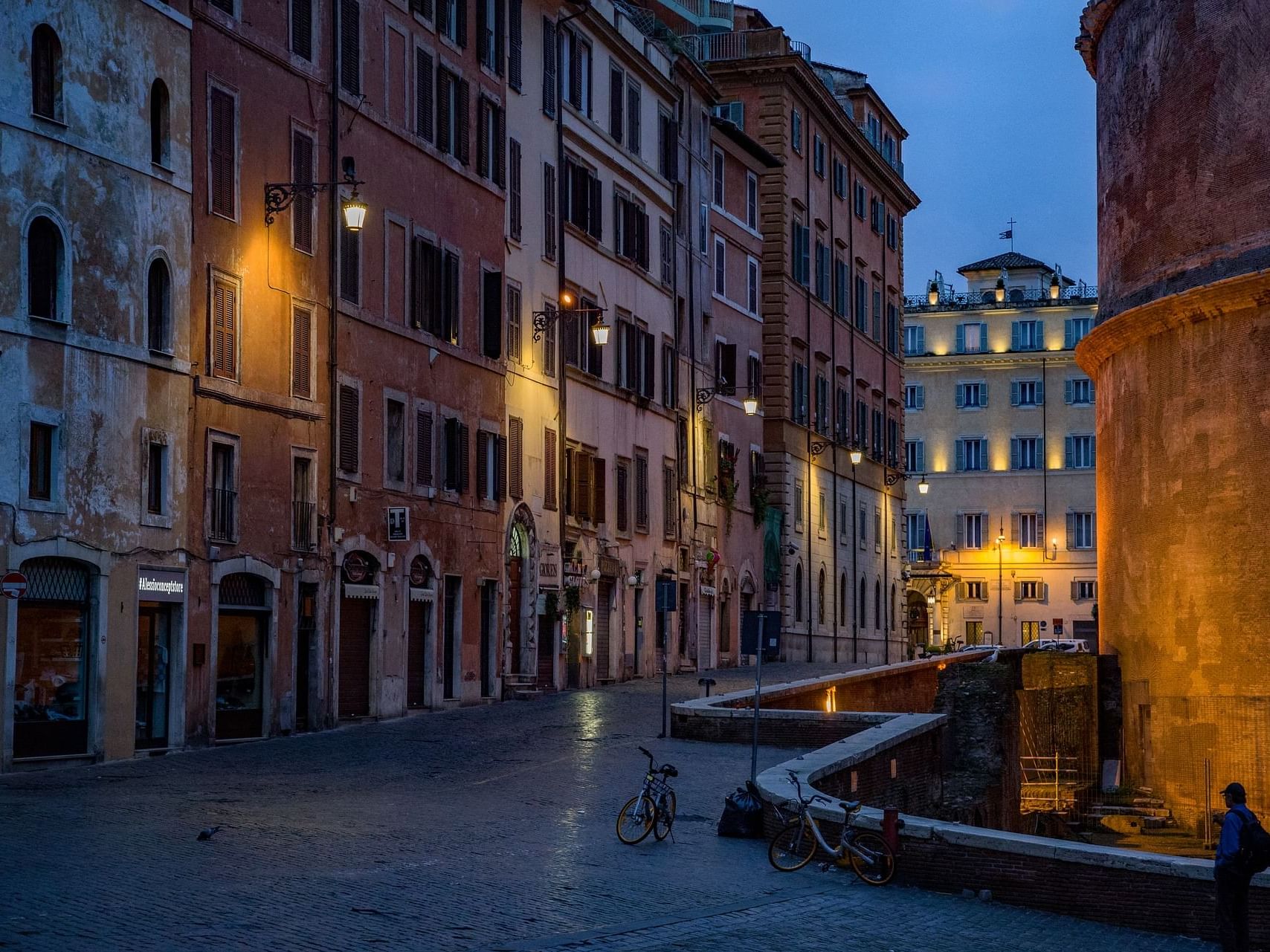 A serene Rome street at dusk with a bicycle and pedestrians strolling along near Bettoja Hotel Massimo D´Azeglio