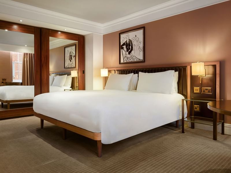 Elegant room with large bed, mirror, and artwork at The May Fair Hotel, London.