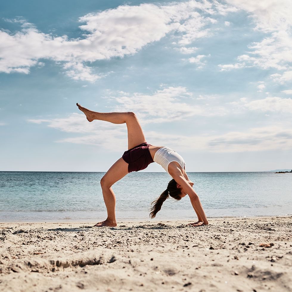 A lady in a Yoga Pose at a beach near Falkensteiner Hotels