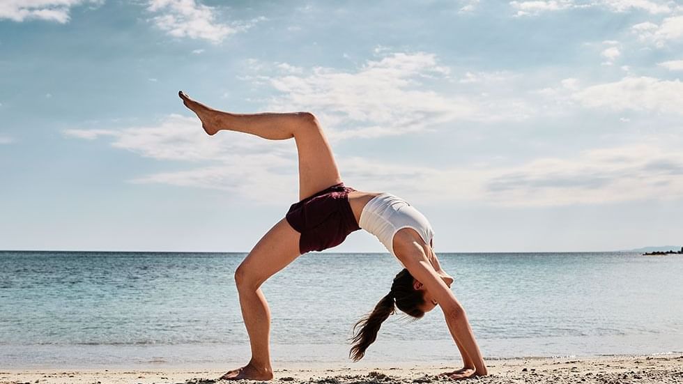 A lady in a Yoga Pose at a beach near Falkensteiner Hotels