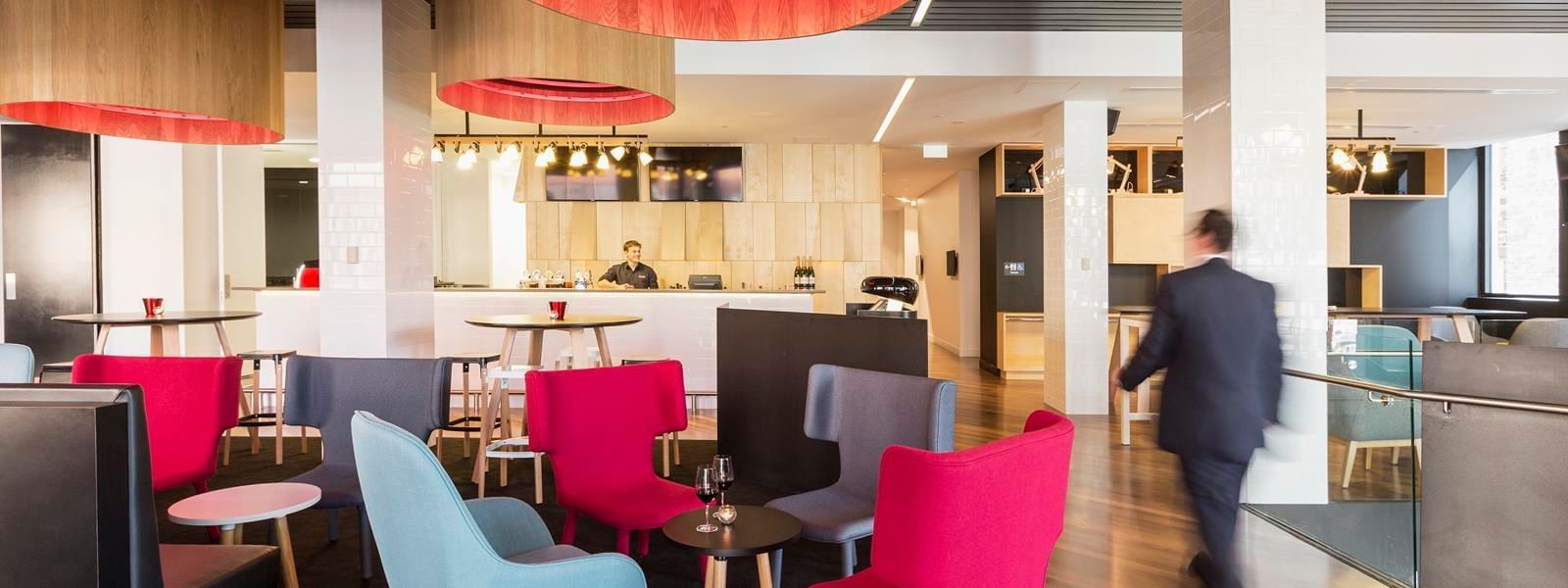 Guest walking through Level One Bar, surrounded by stylish seating and distinctive lighting at Ibis Adelaide