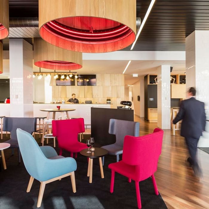 Guest walking through Level One Bar, surrounded by stylish seating and distinctive lighting at Ibis Adelaide