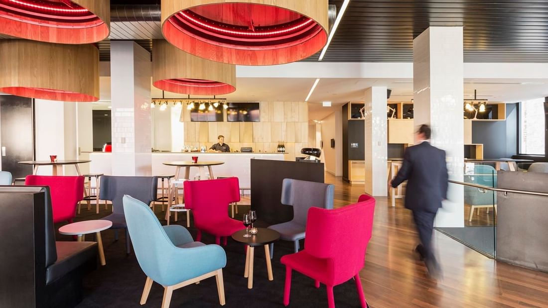 Guest walking through Level One Bar, surrounded by stylish seating and distinctive lighting at Ibis Adelaide