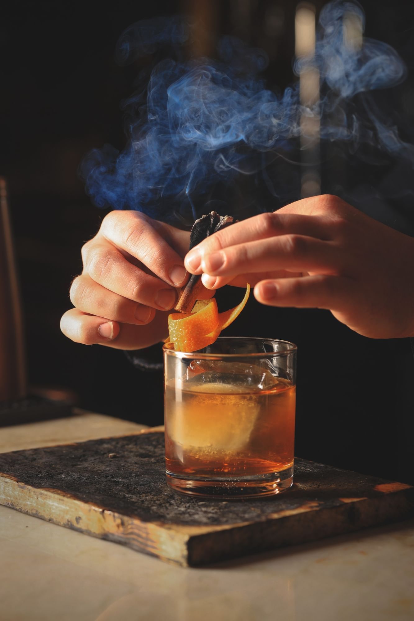 Lorem ipsum Two hands over a clear glass filled with a drink and adding a garnish on top