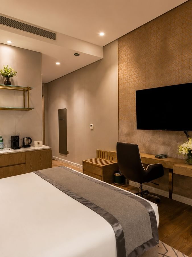King bed facing wall-mounted television and work desk with chair in Deluxe Room at Naviti by Warwick Jeddah