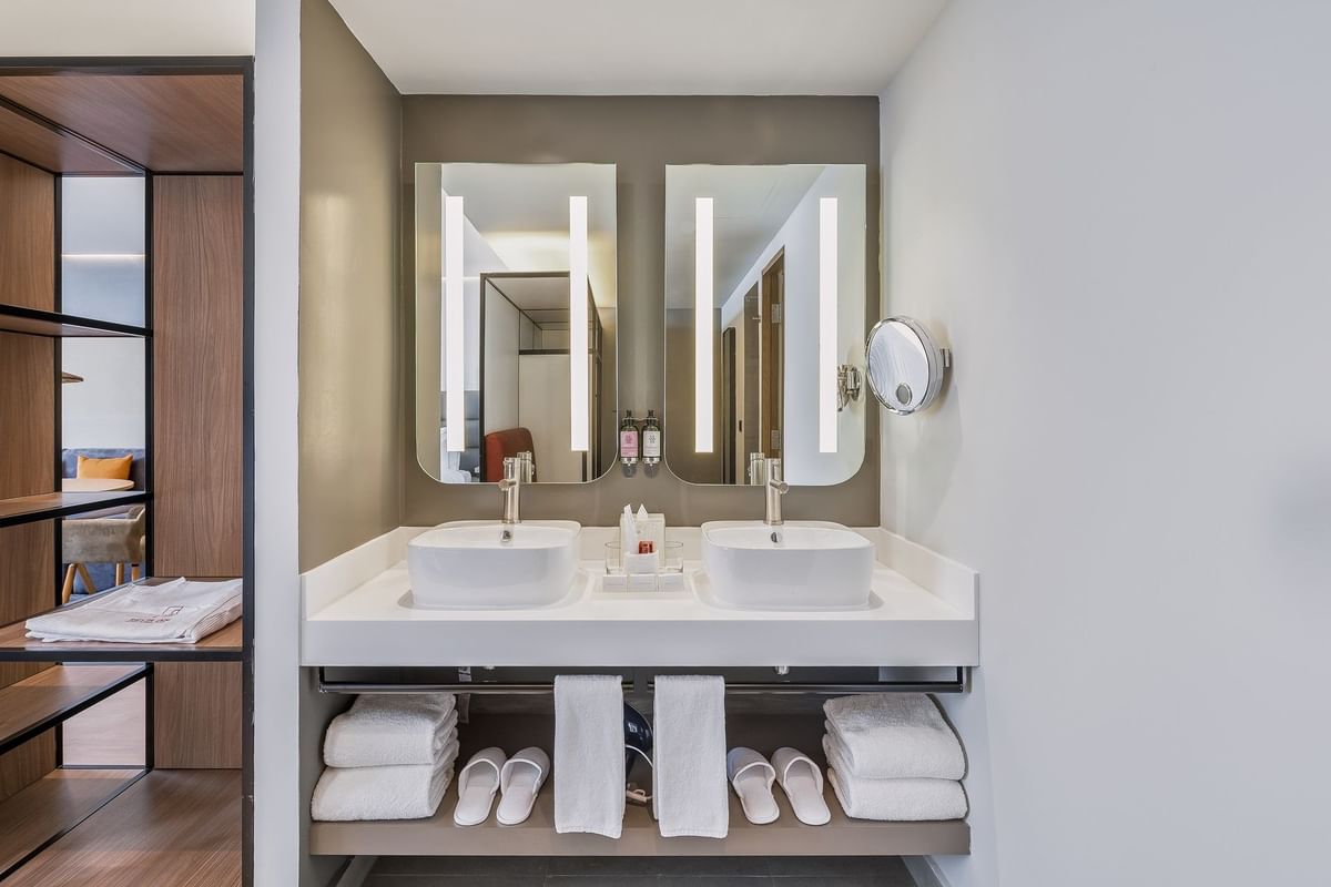 Dos lavabos blancos sobre tocadores con espejos rectangulares a juego en baño moderno de Fiesta Inn