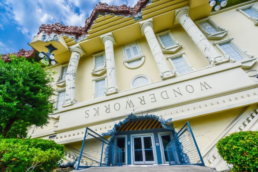 An upside down building with columns and street lamps hanging from the roof with a sign that reads WONDERWORKS. 