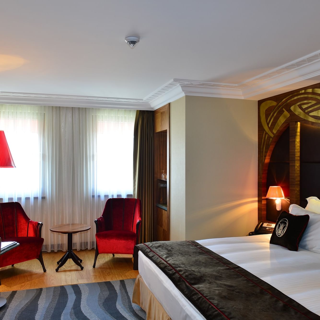 Chambre élégante dotée d'un grand lit, de chaises, d'un bureau et d'une tête de lit originale au Warwick Ankara.