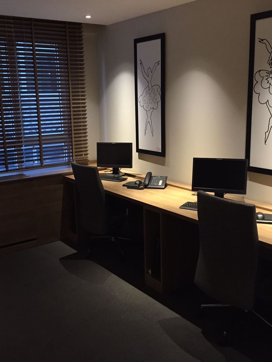 Modern desks with black chairs by sketch art under soft light in a business center at Warwick Ankara