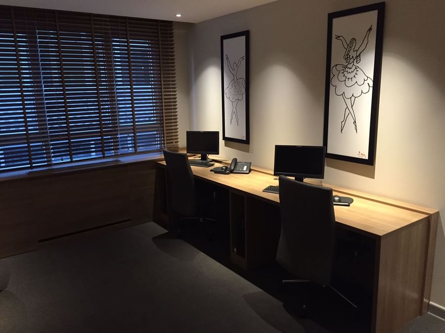 Modern desks with black chairs by sketch art under soft light in a business center at Warwick Ankara