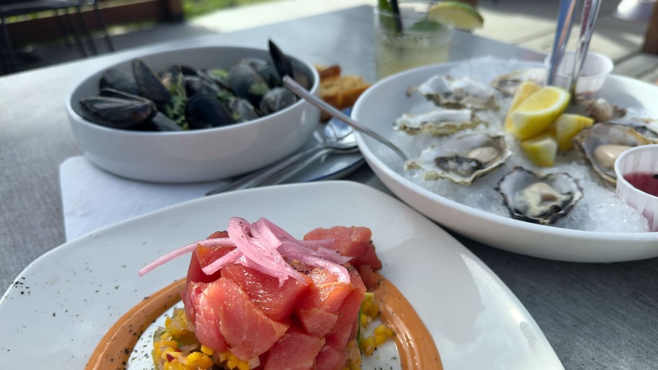 A table set with seafood dishes including oysters on ice, mussels, and a plate of tuna.