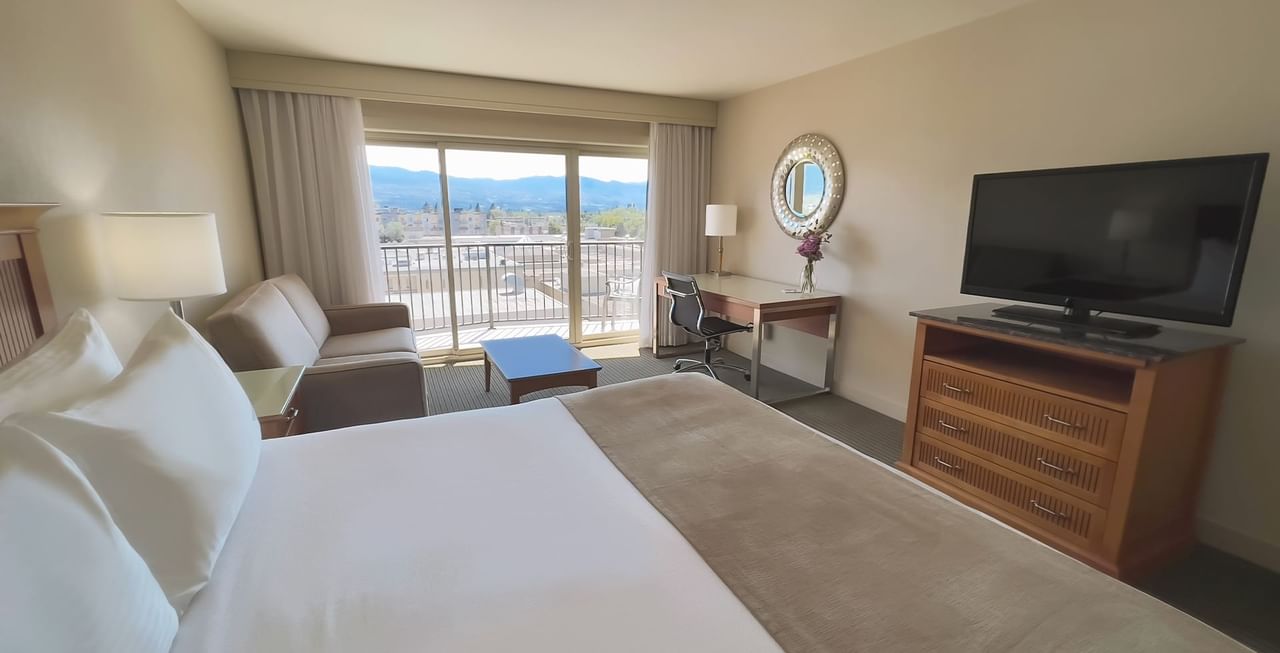 Hotel room with king bed, sofa, mirror, work desk, chair, and TV