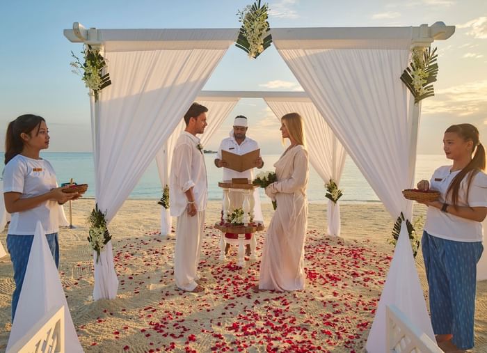 Couple standing under a beach wedding canopy at Grand Park Kodhipparu, Maldives