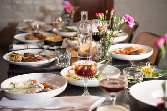 Dining table featuring various dishes, cocktails, glasses of water, and floral vases at Hotel Sorrento