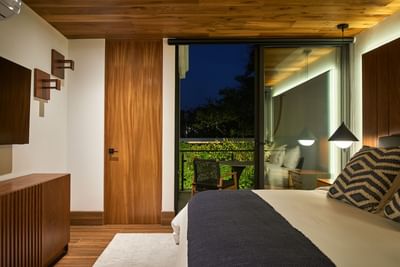 Bedroom with a large bed, wooden furniture, and a balcony with a small table in Casa Cielo at Singular Signature Residences