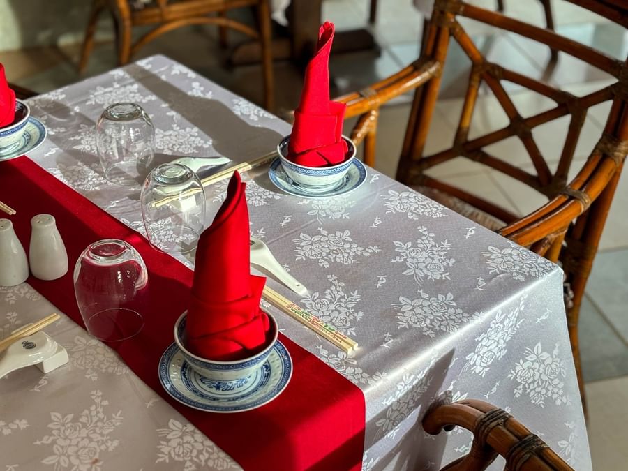 Elegantly set table with floral tablecloth, red napkins, and Asian-inspired dishes at The Naviti Resort Fiji.