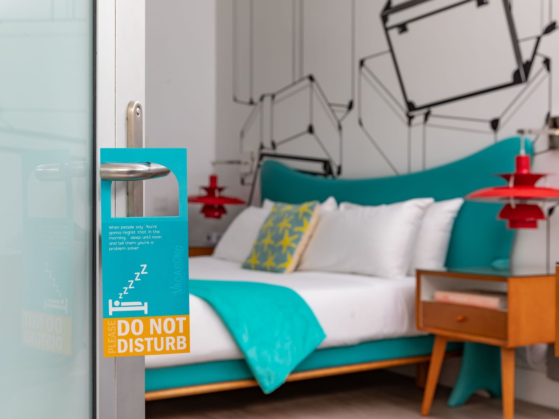 DO not disturb sign places on the door handle that is ajar with the King size bed in the background
