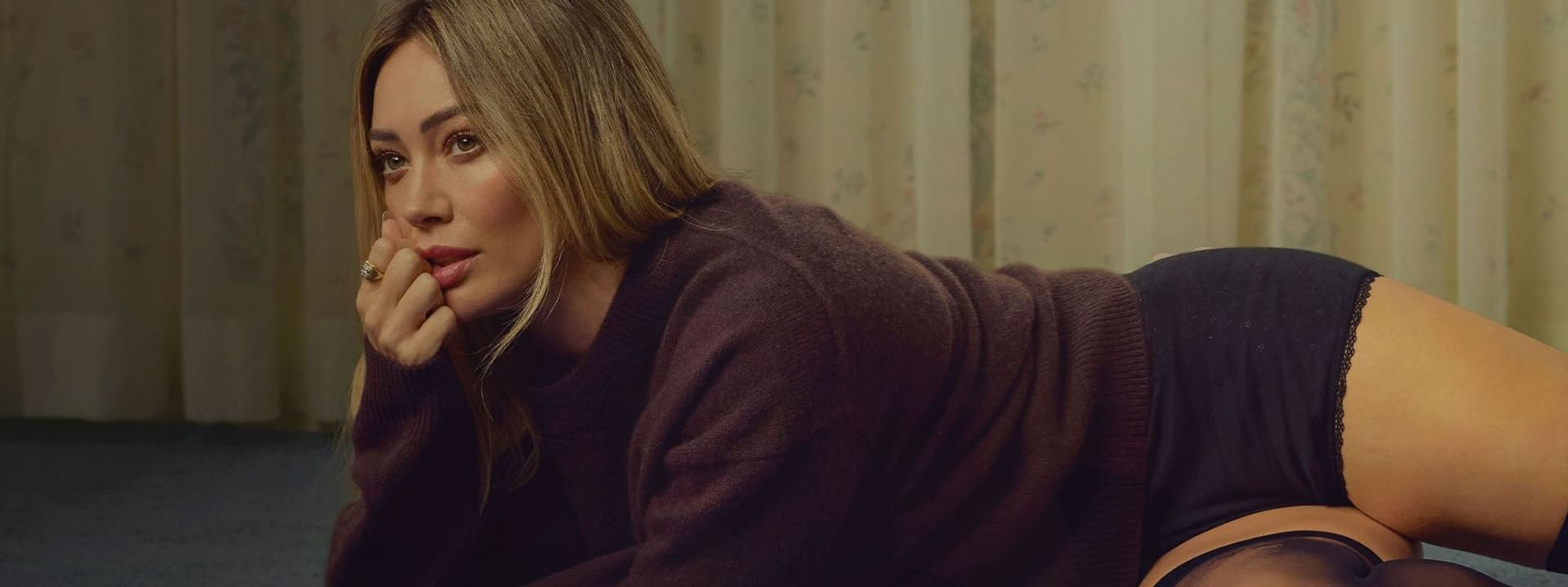 Hilary Duff lying on a floor in a relaxed pose for The Lucky Me Tour 2026.