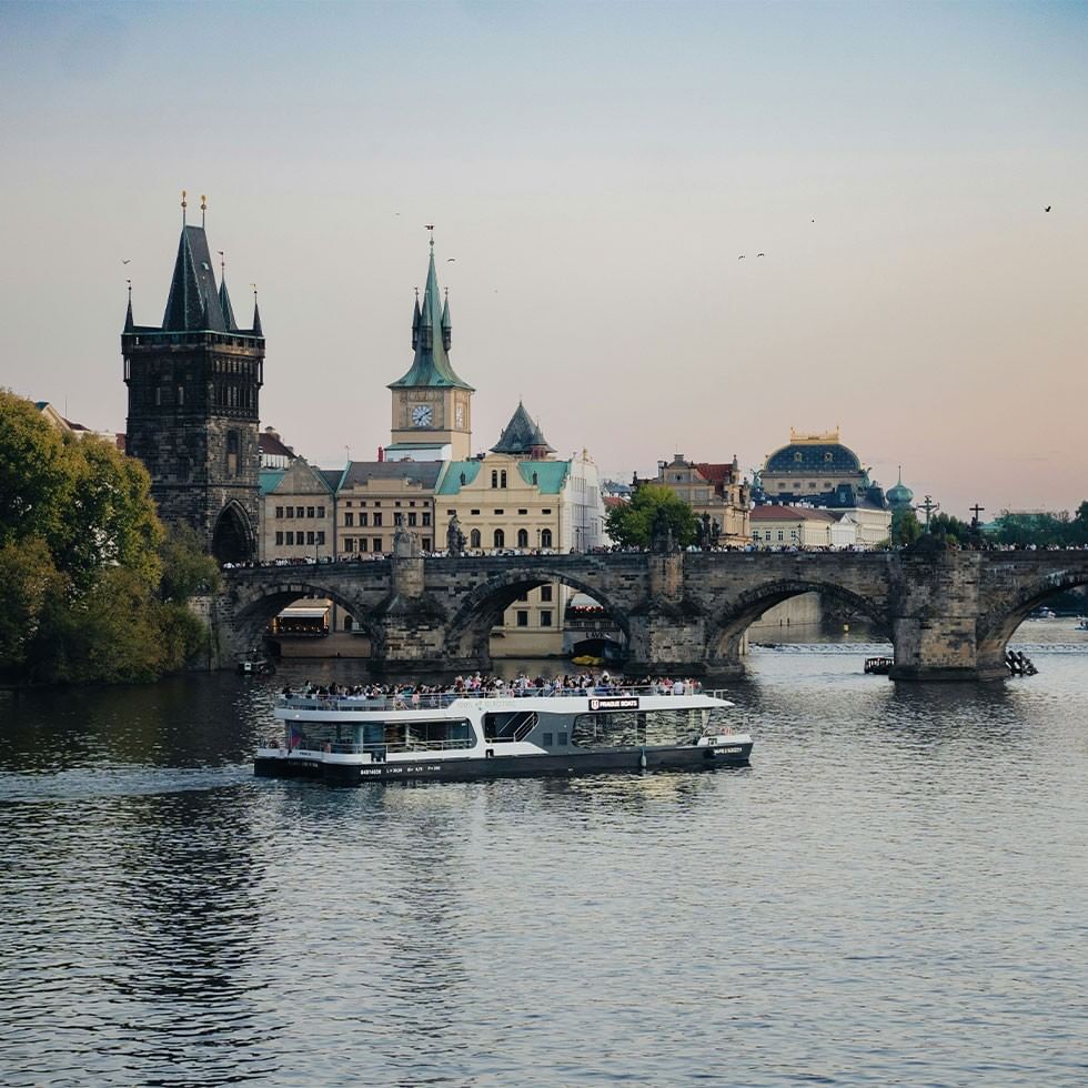 Crociera natalizia sulla Moldava con vista sul ponte storico e edifici gotici.