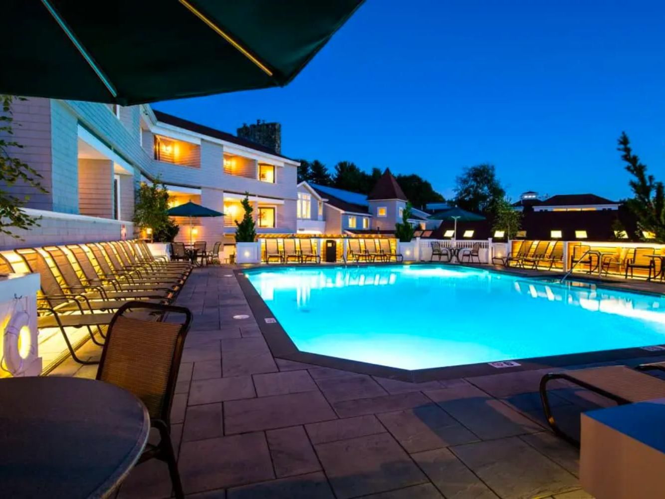 An outdoor swimming pool with clear blue water, surrounded by lounge chairs and umbrellas at Meadowmere Resort