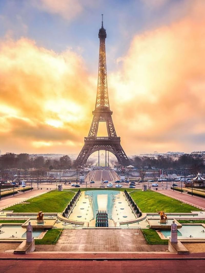 Eiffel Tower by a water garden under a golden sunset sky near Warwick Paris Champs Elysées
