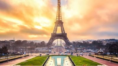 Eiffel Tower by a water garden under a golden sunset sky near Warwick Paris Champs Elysées