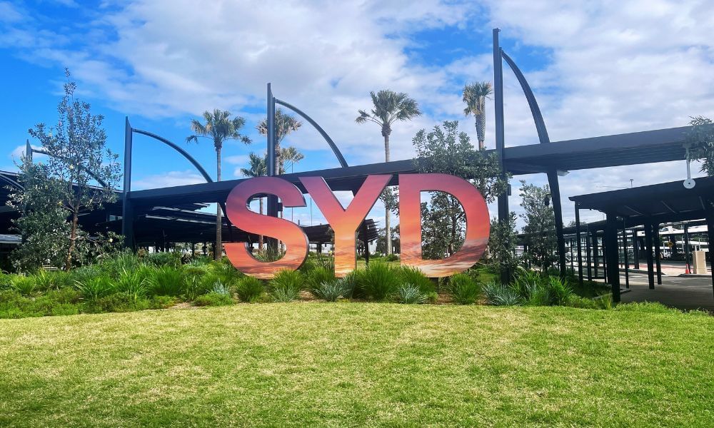 SYD sign on the green grass at Sydney Airport outside International Arrivals