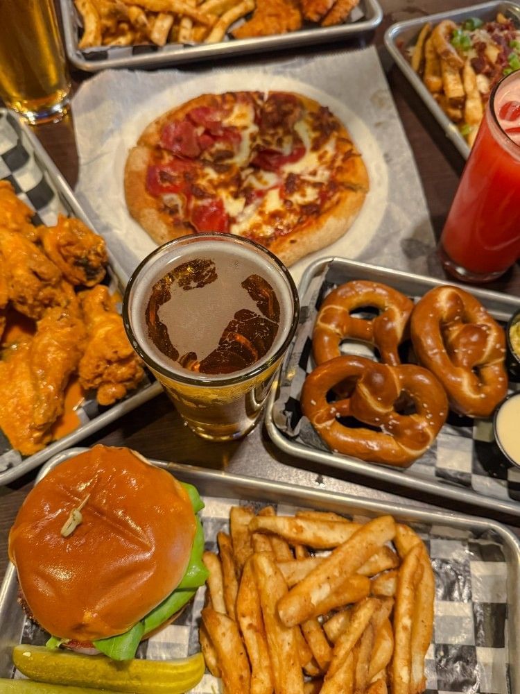 An overhead shot of a table covered in plates of bar food, including pretzels, pizza, wings, burgers, and beer at Zebra's Sports Bar and Grille, a great sports bar in Orlando..