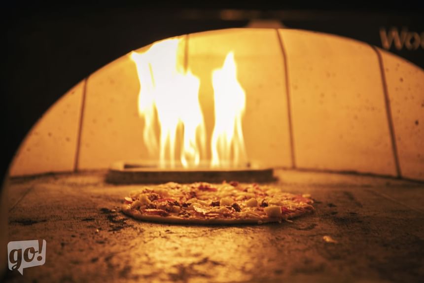 a pizza cooking in a brick oven
