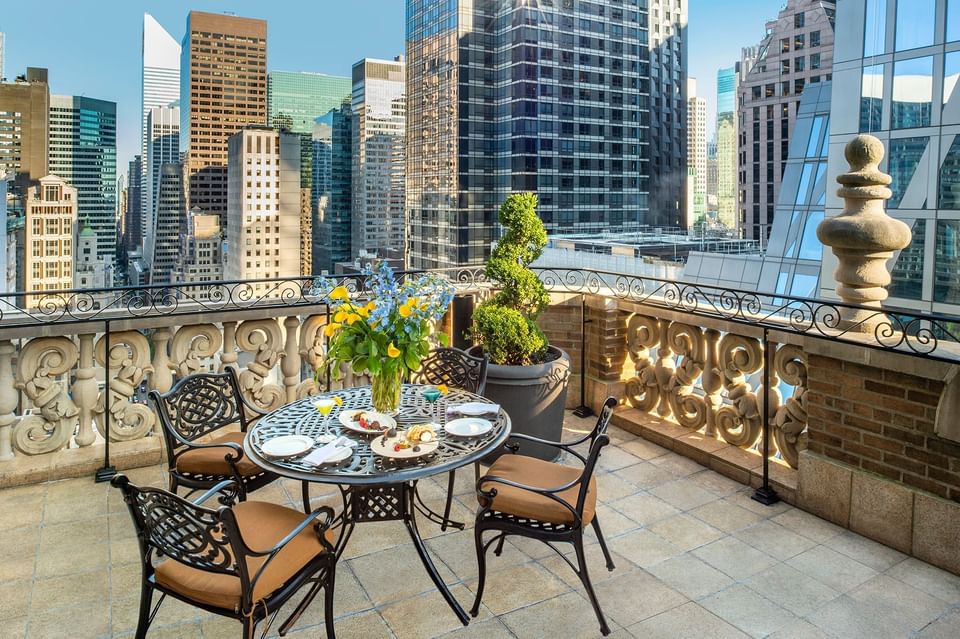 Elegant rooftop terrace features a set table and chairs overlooking a city skyline at Warwick New York