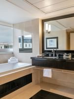 Une salle de bains luxueuse avec baignoire, double vasque et grand miroir au Warwick Champs-Élysées Paris.